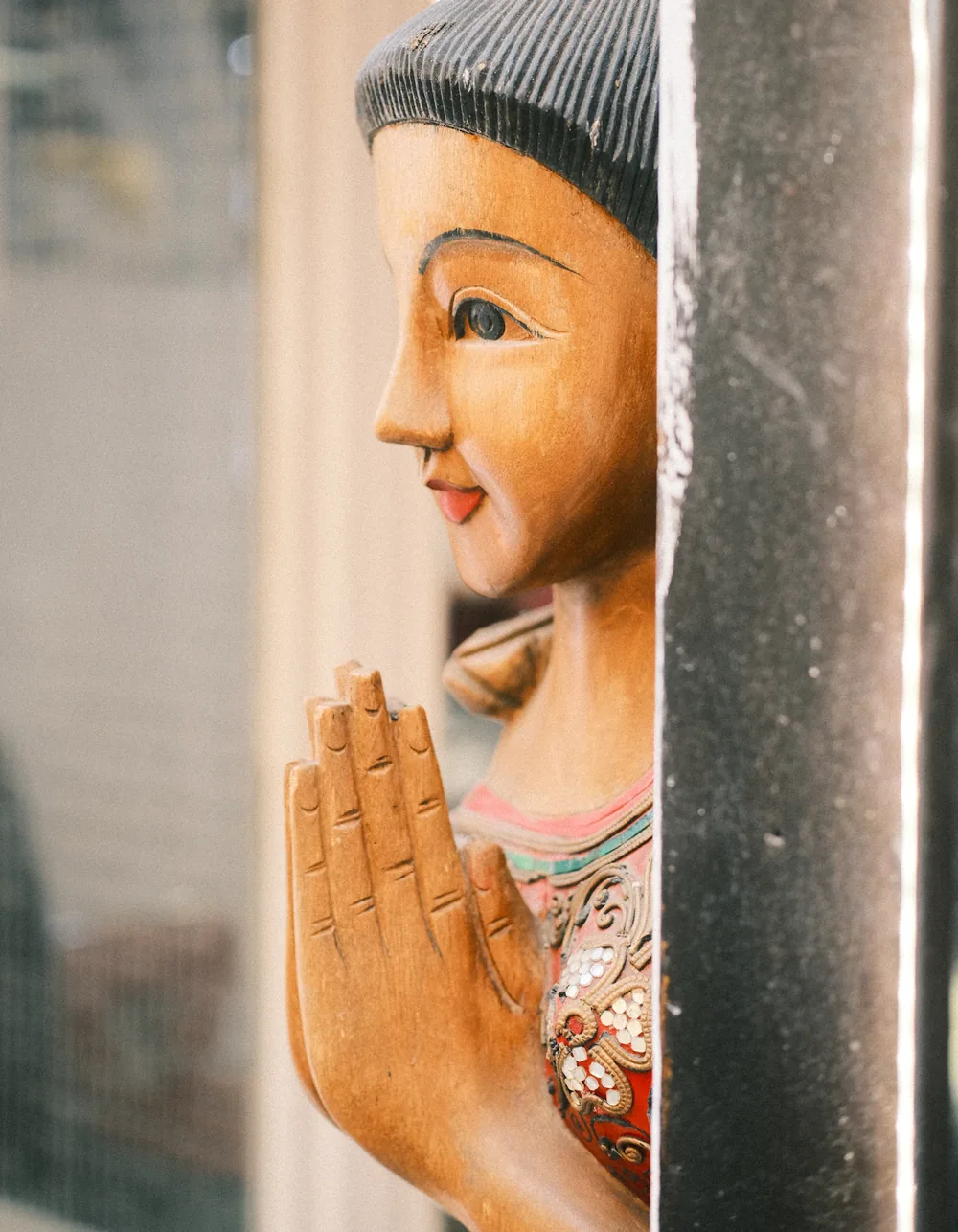 Thailändische Holzfigur mit zum Wai gefalteten Händen